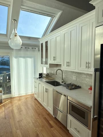 Kitchen remodel with white cabinets under two skylights