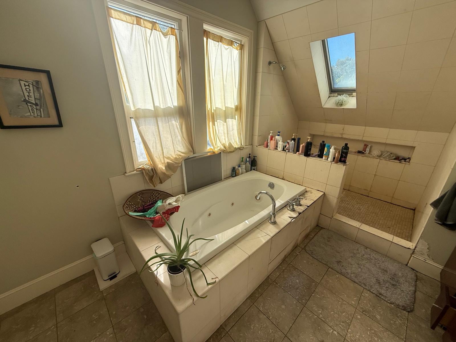Bathroom before remodeling: jetted tub, open shower and skylight with older tile