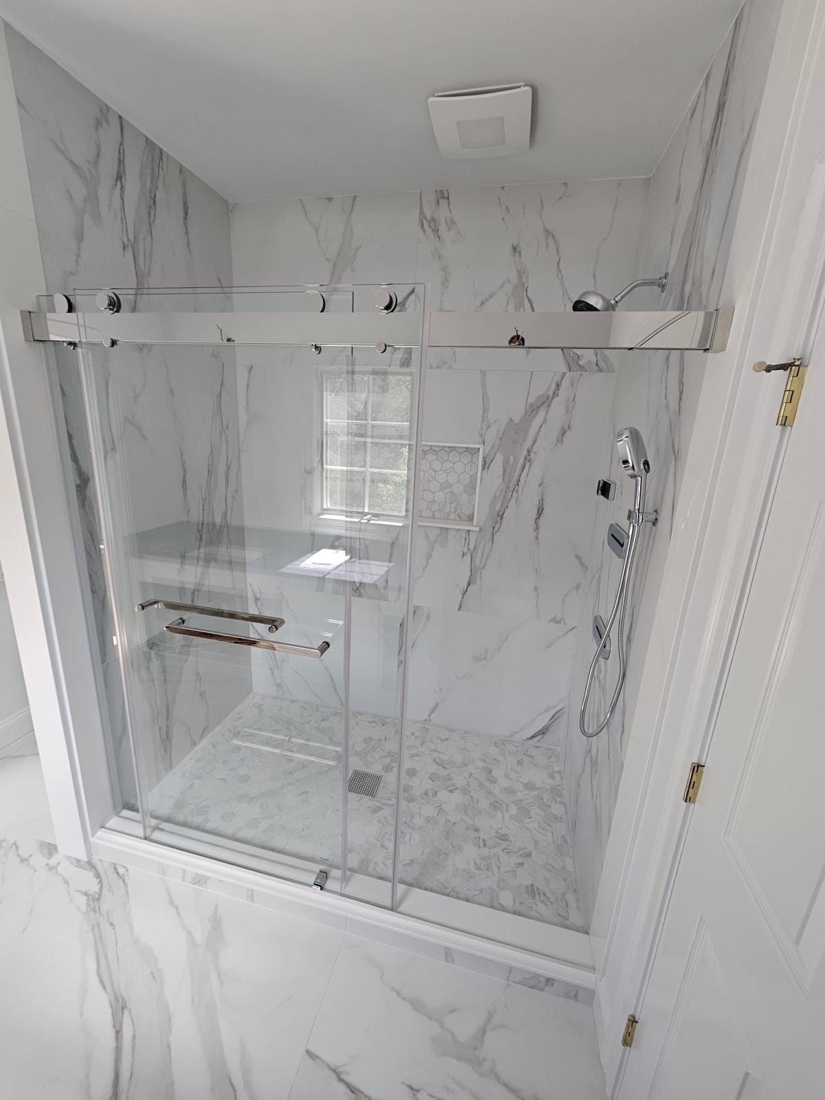 Marble-look tile shower with a sliding glass door and chrome fixtures