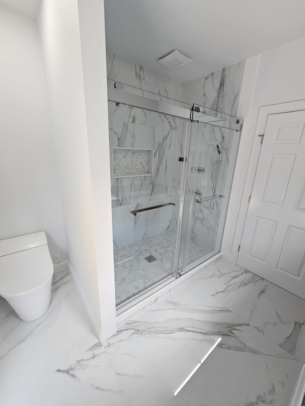 White marble-look shower with a sliding glass door