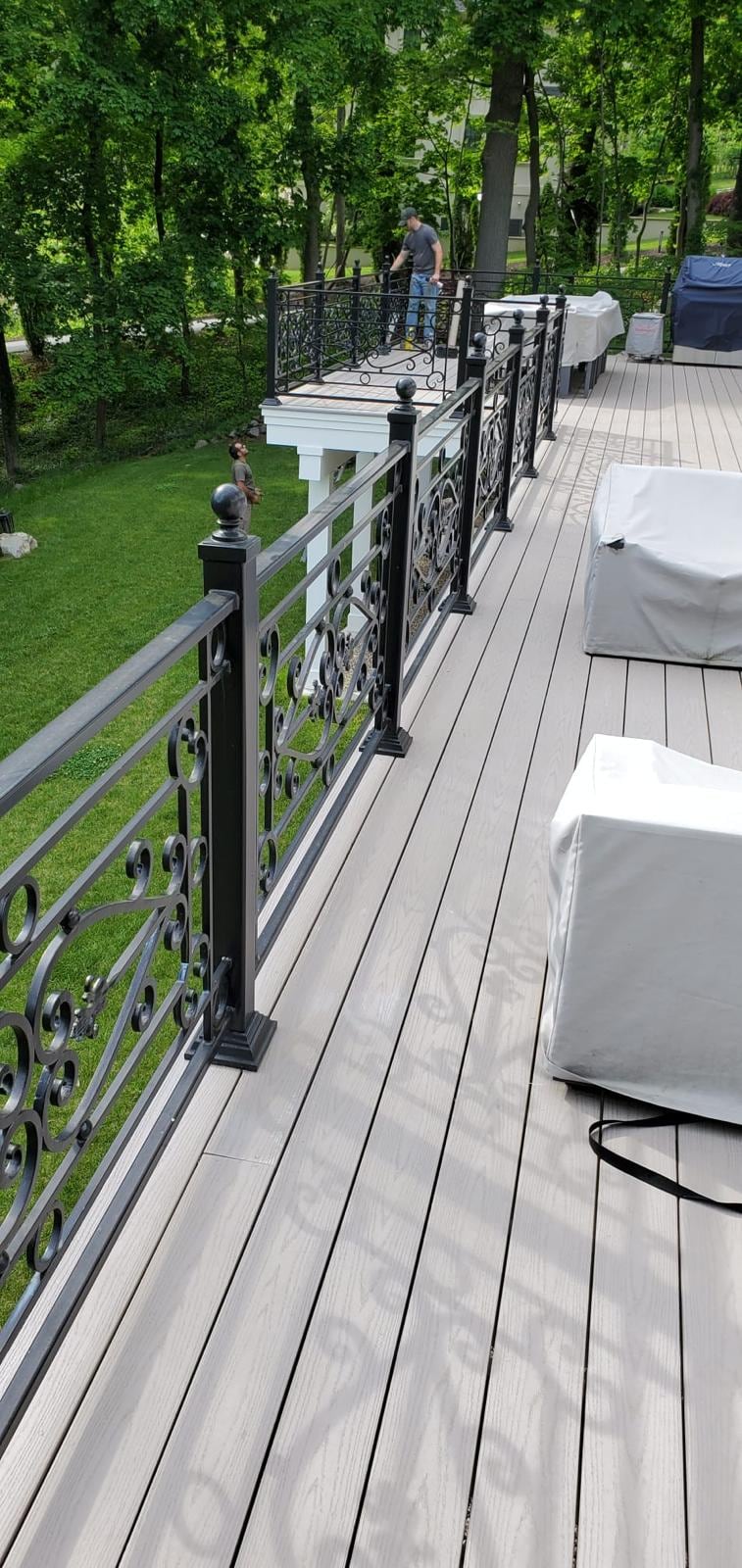 Composite deck with a black metal railing overlooking a wooded yard