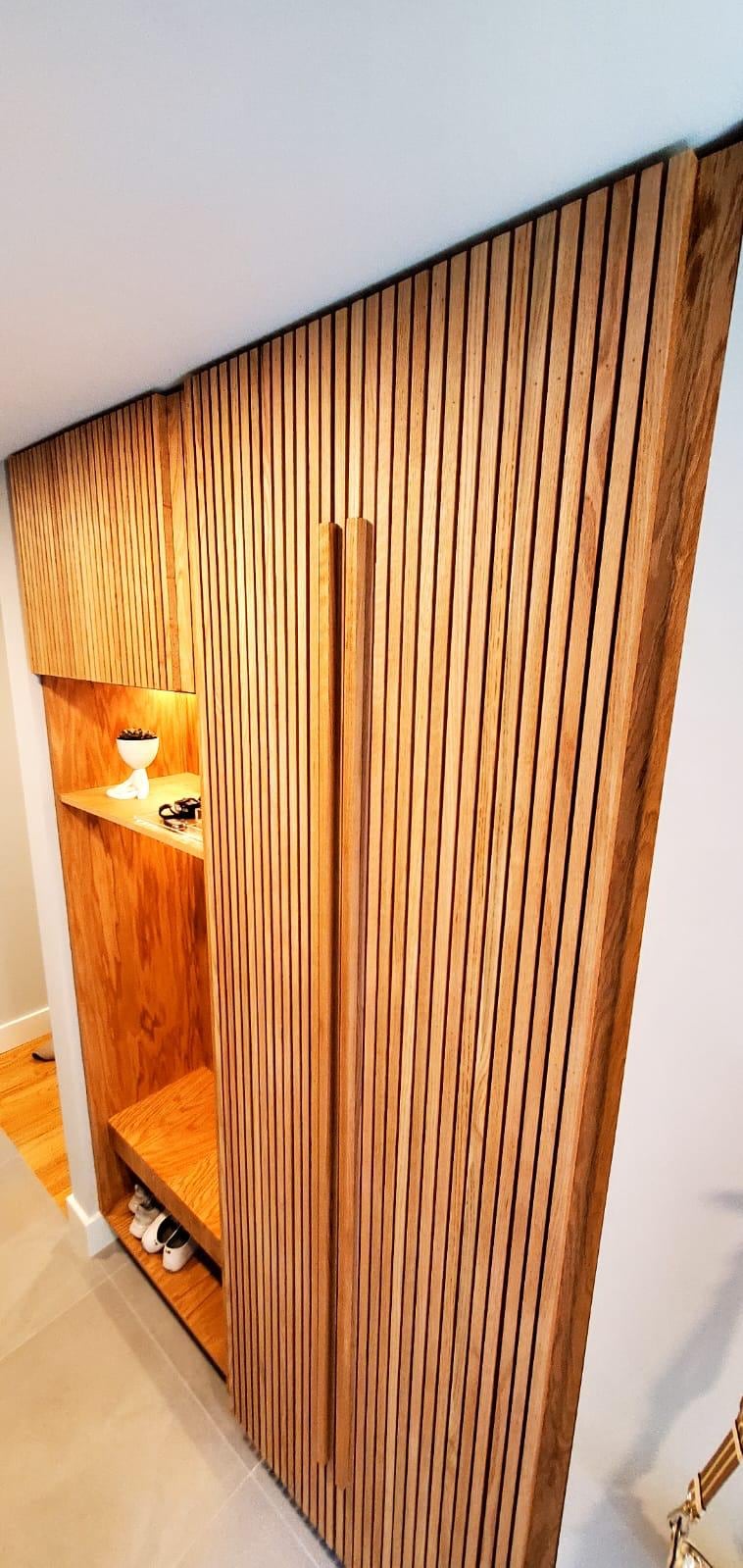 Vertical wood slat wall with a lit display niche in a remodeled entry