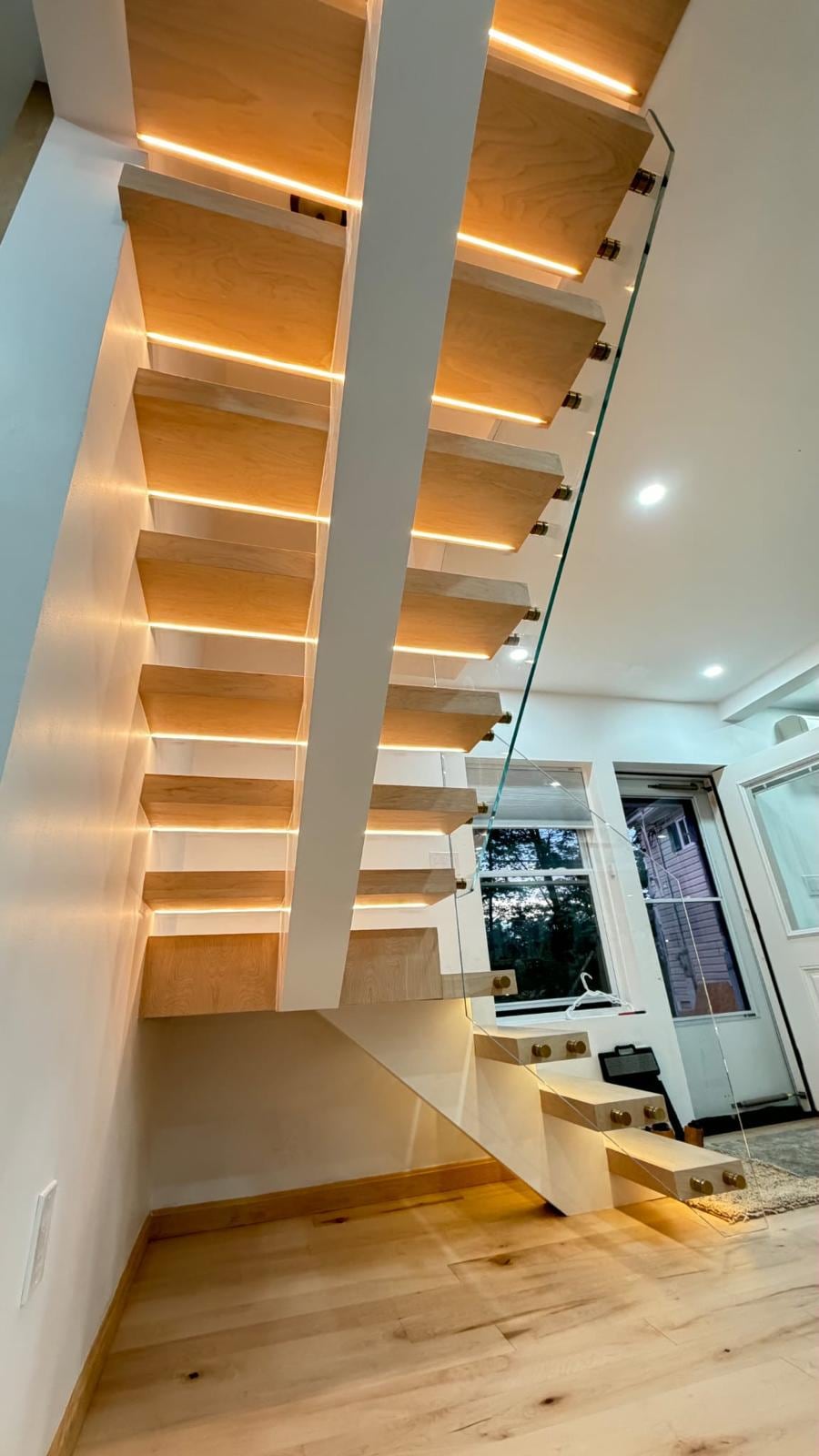 Floating wood stairs with LED-lit treads and a glass railing