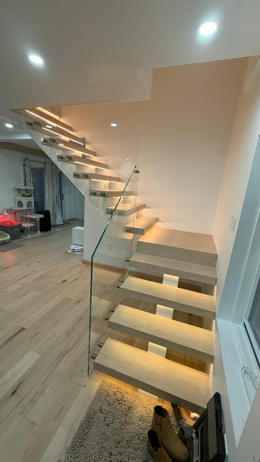 Floating stairs with lit treads turning up along a white wall