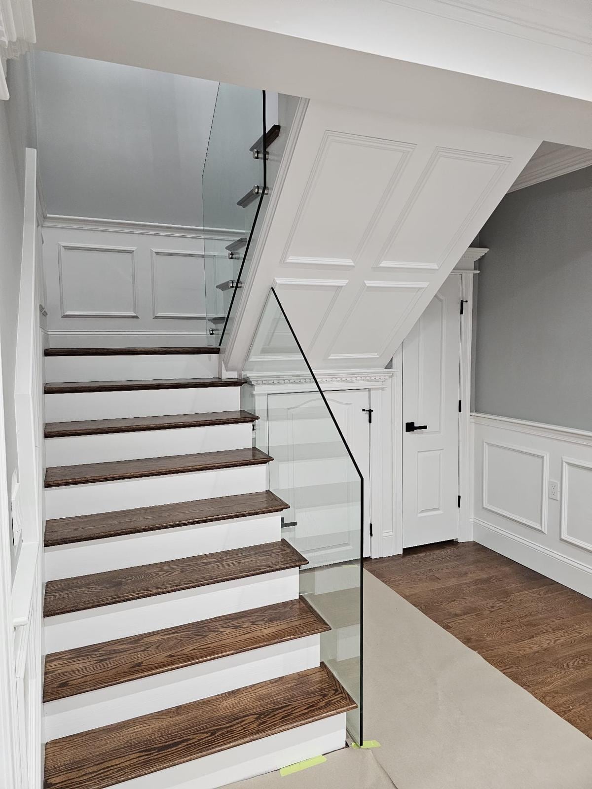 Interior stairs with wood treads, white risers, a glass railing and wainscoting