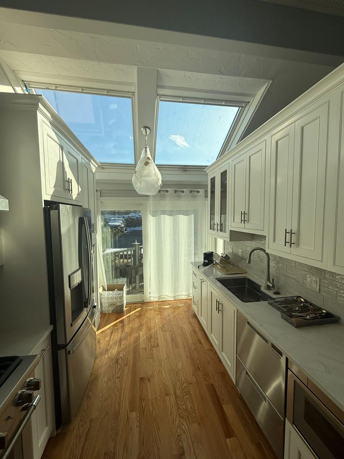 White kitchen with skylights, a pendant light and built-in cabinets