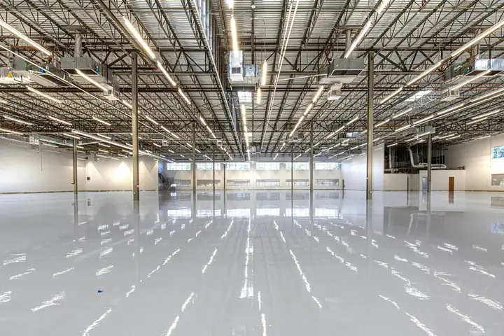 Glossy light-gray coated concrete floor reflecting overhead lights in a large building