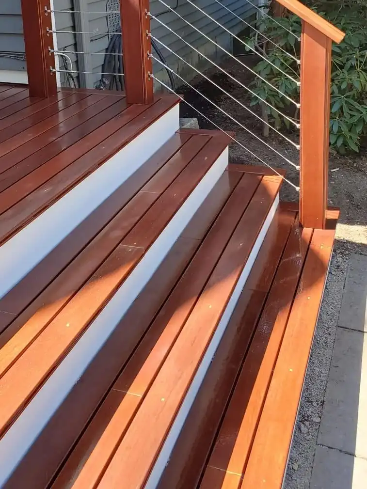 Hardwood deck and stairs with white risers and stainless cable railing on wood posts