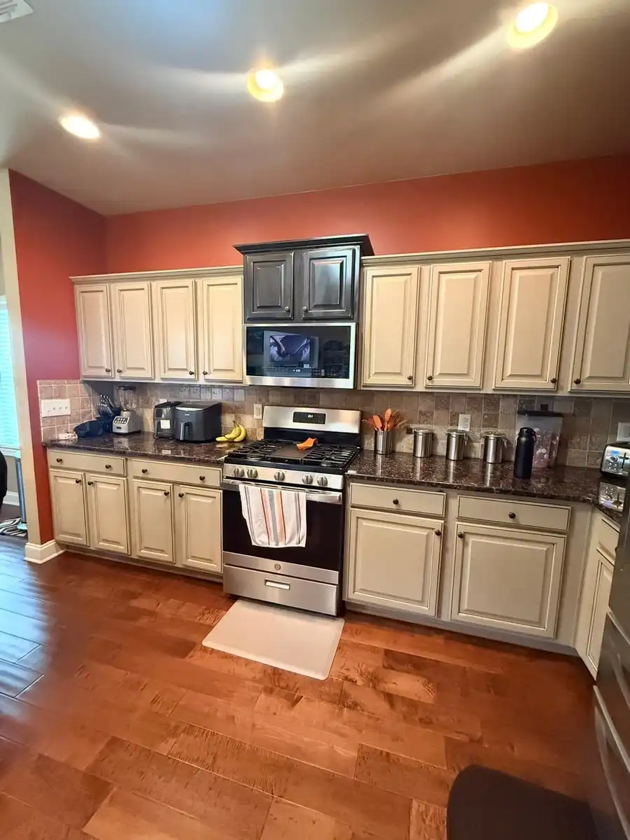 Kitchen before remodeling: cream cabinets, dark granite counters and orange walls